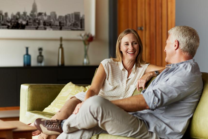 A man and woman sitting on a couch, laughing together